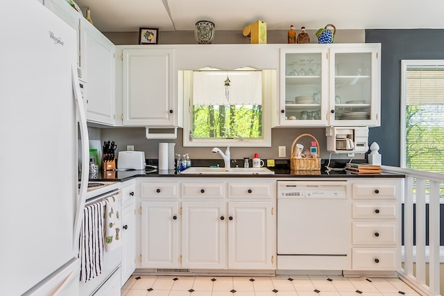 kitchen featuring glass insert cabinets, white appliances, a sink, dark countertops, and white cabinets
