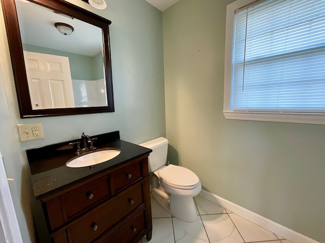 bathroom with marble finish floor, toilet, vanity, and baseboards