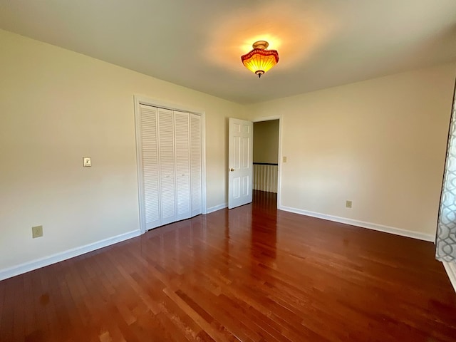 unfurnished bedroom with baseboards, a closet, and wood finished floors