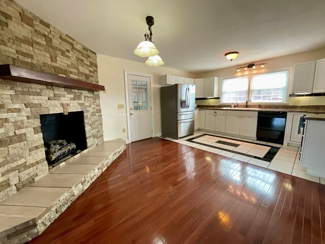 kitchen featuring white cabinetry, stainless steel fridge, a sink, dishwasher, and wood finished floors