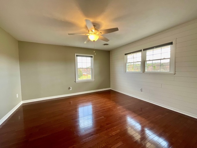 spare room featuring dark wood-style flooring, visible vents, baseboards, and ceiling fan