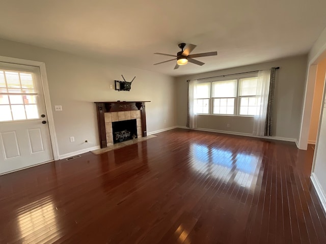 unfurnished living room with visible vents, a tile fireplace, baseboards, a ceiling fan, and dark wood-style floors
