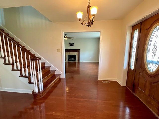 entrance foyer featuring a tiled fireplace, dark wood-type flooring, stairway, and visible vents