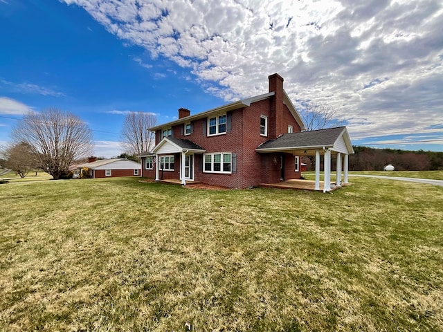back of property with a lawn, a chimney, and brick siding