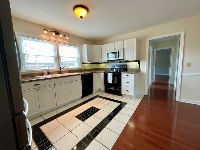 kitchen featuring baseboards, dark countertops, and black appliances