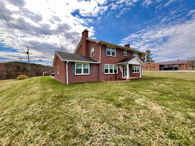 rear view of house with brick siding, a yard, and a chimney
