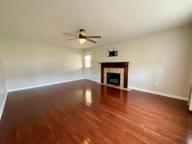 unfurnished living room featuring visible vents, a tile fireplace, baseboards, ceiling fan, and wood finished floors