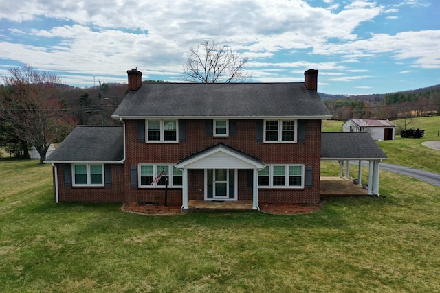 rear view of property featuring a chimney, brick siding, and a yard