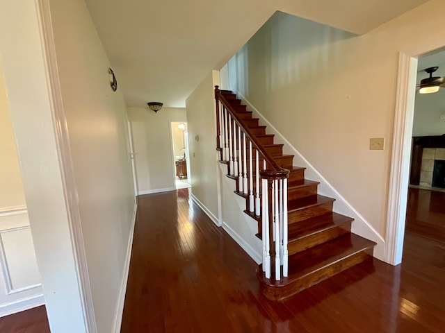 stairs with a tile fireplace, hardwood / wood-style flooring, and baseboards