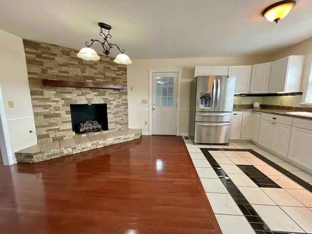 kitchen featuring pendant lighting, stainless steel fridge with ice dispenser, baseboards, white cabinets, and light wood-style floors