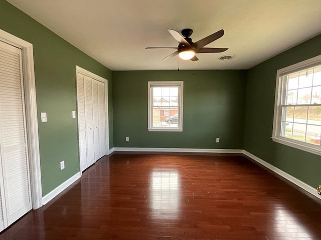 empty room with dark wood-style floors, baseboards, and visible vents