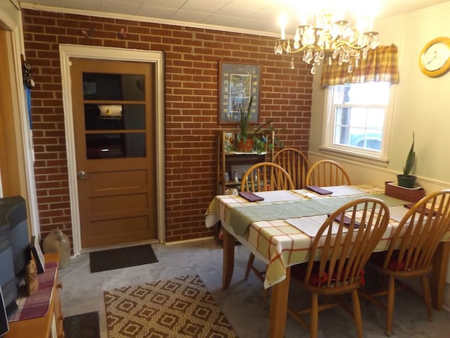 carpeted dining room with crown molding, brick wall, and an inviting chandelier