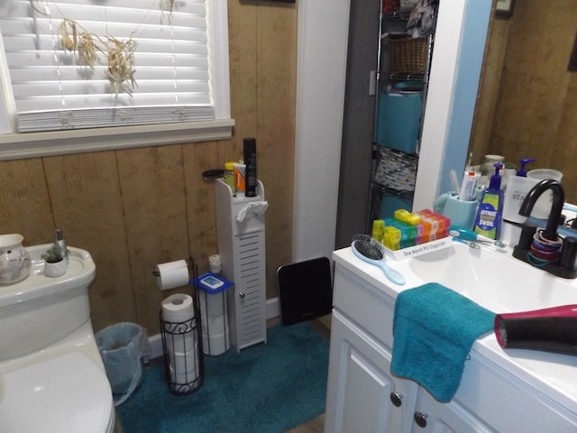 bathroom featuring toilet, vanity, and wooden walls