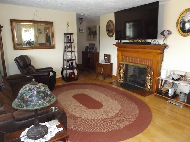 living room featuring a fireplace, wood-type flooring, and a textured ceiling