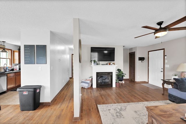 178 Woodside Dr, Chilhowie, VA 24319 - living room with a ceiling fan, light wood-style floors, baseboards, a glass covered fireplace, and a textured ceiling