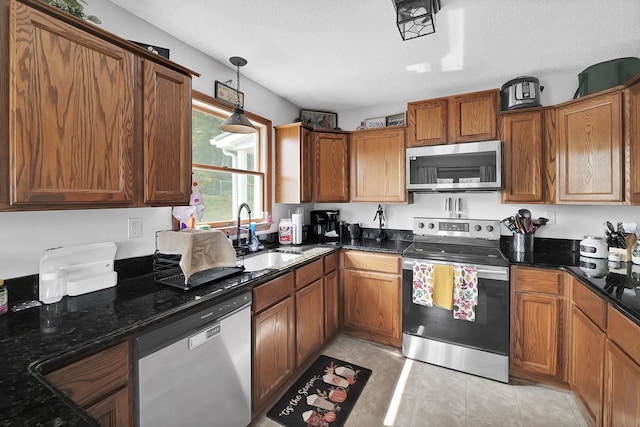 178 Woodside Dr, Chilhowie, VA 24319 - kitchen featuring appliances with stainless steel finishes, a sink, brown cabinetry, dark stone countertops, and decorative light fixtures