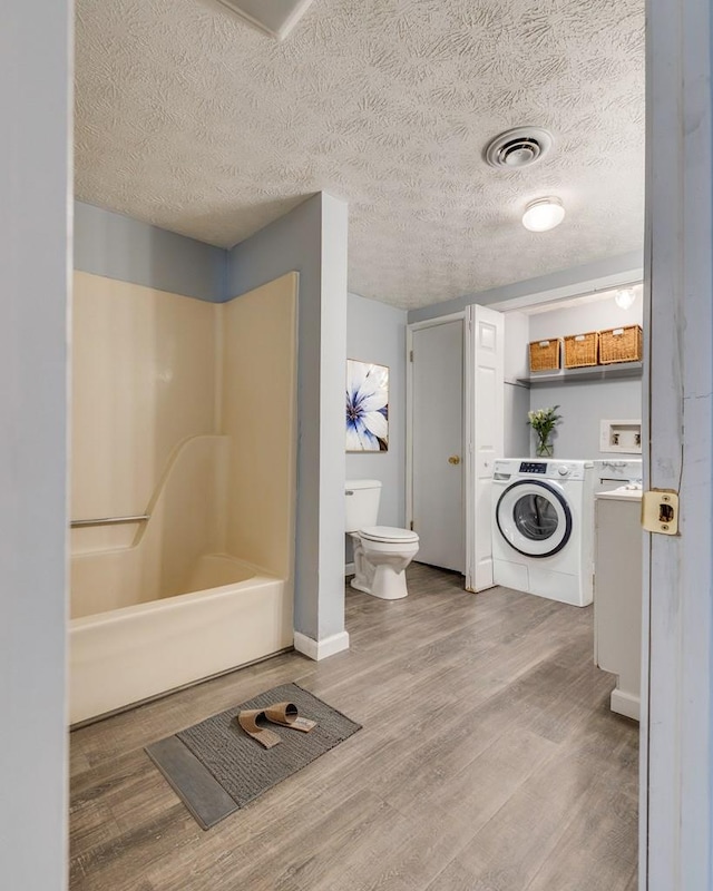 103 Whites Subdivision Rd, Cedar Bluff, VA 24609 - bathroom with washer / dryer, toilet, wood finished floors, baseboards, and a textured ceiling