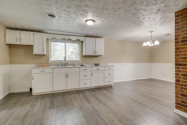 103 Whites Subdivision Rd, Cedar Bluff, VA 24609 - kitchen featuring a sink, light wood-style flooring, white cabinets, a textured ceiling, and a chandelier