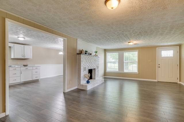 103 Whites Subdivision Rd, Cedar Bluff, VA 24609 - unfurnished living room featuring a textured ceiling, baseboards, ornamental molding, dark wood finished floors, and a brick fireplace