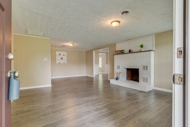 103 Whites Subdivision Rd, Cedar Bluff, VA 24609 - unfurnished living room with a textured ceiling, wood finished floors, baseboards, and a brick fireplace