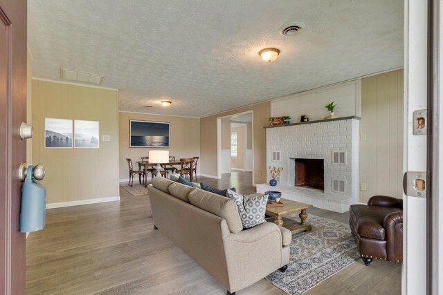 103 Whites Subdivision Rd, Cedar Bluff, VA 24609 - living room with light wood-type flooring, a textured ceiling, baseboards, and a brick fireplace
