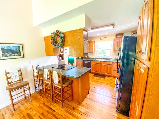 1476 E Blue Grass Trl, Bland, VA 24315 - kitchen featuring black appliances, a peninsula, a sink, a breakfast bar area, and light wood-type flooring