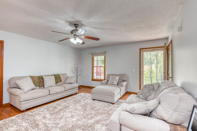 living room with baseboards, wood finished floors, a textured ceiling, and ceiling fan