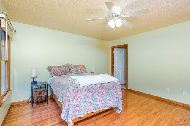 bedroom featuring baseboards, a ceiling fan, wood finished floors, and a textured ceiling
