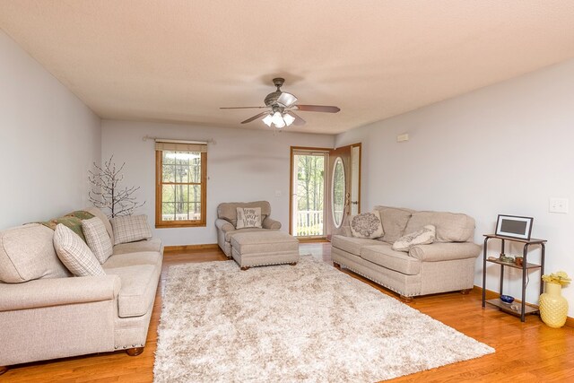 living area with ceiling fan, baseboards, and light wood-style flooring