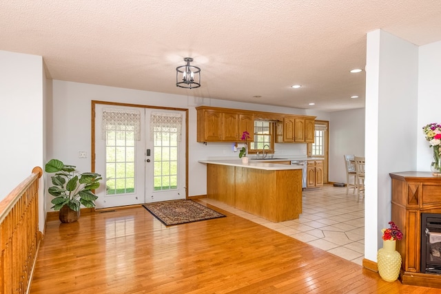 kitchen with recessed lighting, light countertops, a sink, a peninsula, and light wood-style flooring