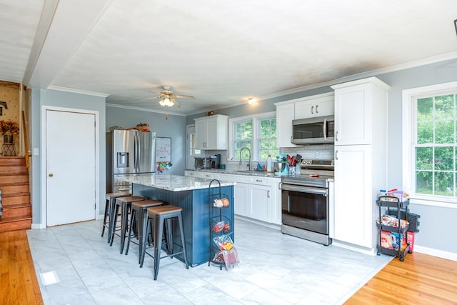 9433 Legend Dr, Glade Spring, VA 24340 - kitchen featuring appliances with stainless steel finishes, a breakfast bar, a kitchen island, white cabinets, and light stone counters