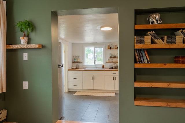 kitchen featuring open shelves, a sink, white cabinetry, dark tile patterned flooring, and freestanding refrigerator