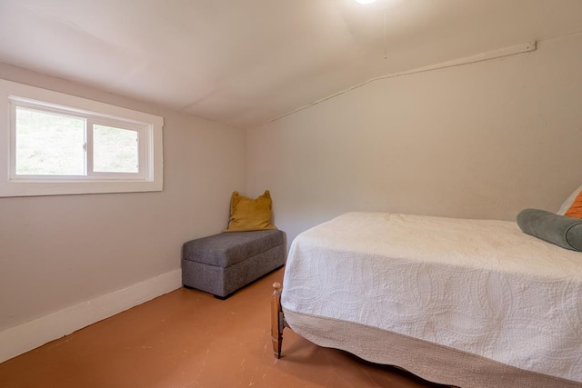 bedroom featuring concrete floors, vaulted ceiling, and baseboards