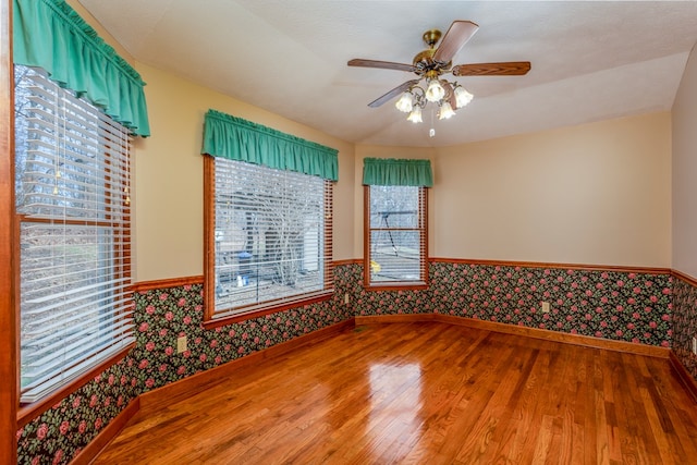 spare room with a wainscoted wall, light wood-style floors, a ceiling fan, and wallpapered walls