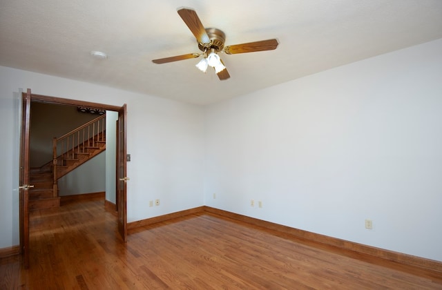 spare room featuring a ceiling fan, baseboards, and wood finished floors