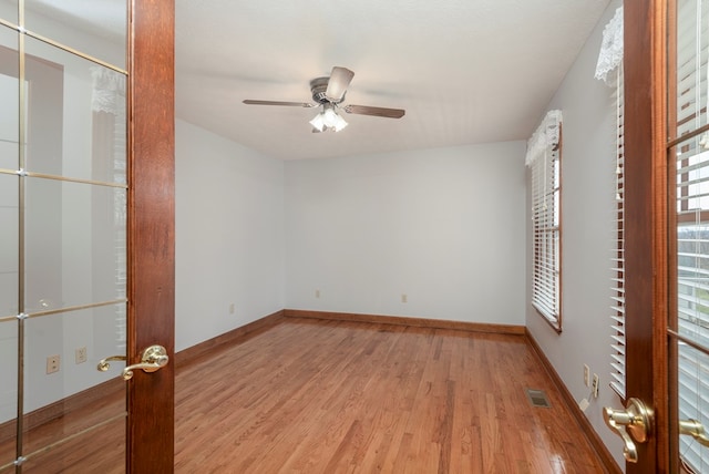 unfurnished room featuring ceiling fan, visible vents, baseboards, and wood finished floors