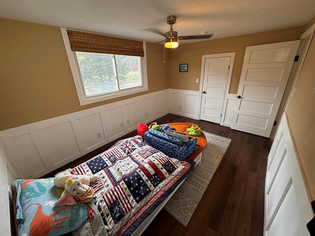 196 Goodwin Rd, Cedar Bluff, VA 24609 - bedroom featuring a wainscoted wall, dark wood-style flooring, a ceiling fan, and a decorative wall