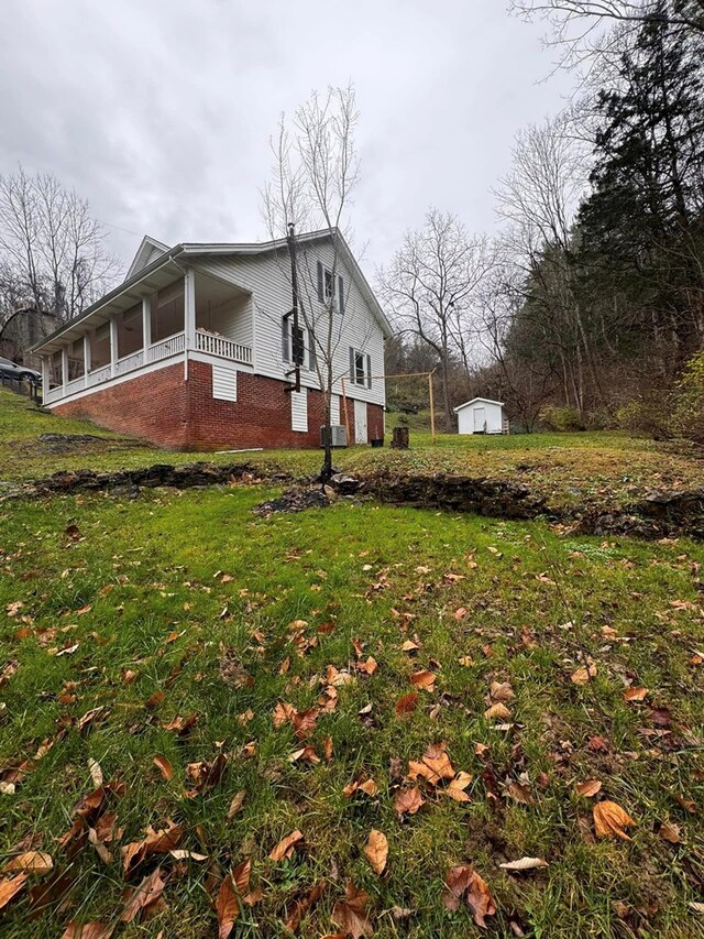 196 Goodwin Rd, Cedar Bluff, VA 24609 - view of home's exterior with brick siding, a storage unit, an outbuilding, and a lawn
