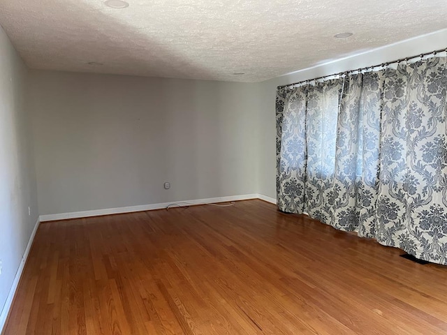 spare room featuring wood-type flooring and a textured ceiling