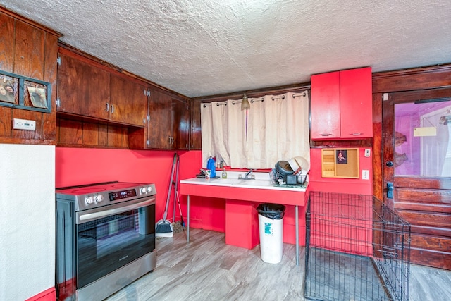 kitchen featuring built in study area, a textured ceiling, light wood finished floors, and stainless steel range with electric cooktop