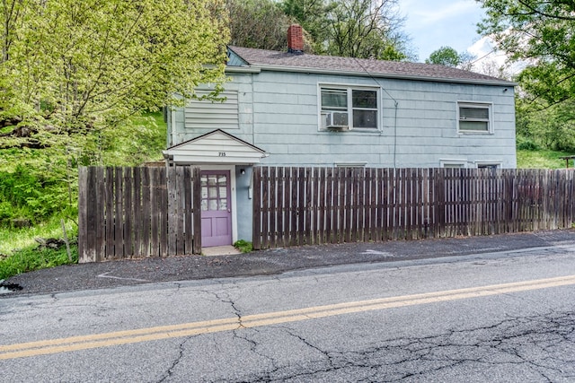 view of front of home with a chimney, cooling unit, and a fenced front yard