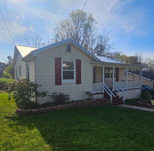 view of front of property featuring a porch, a front yard, and metal roof