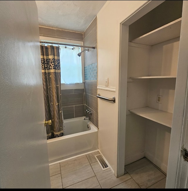 bathroom with tile patterned floors, shower / bath combination with curtain, visible vents, baseboards, and a textured ceiling
