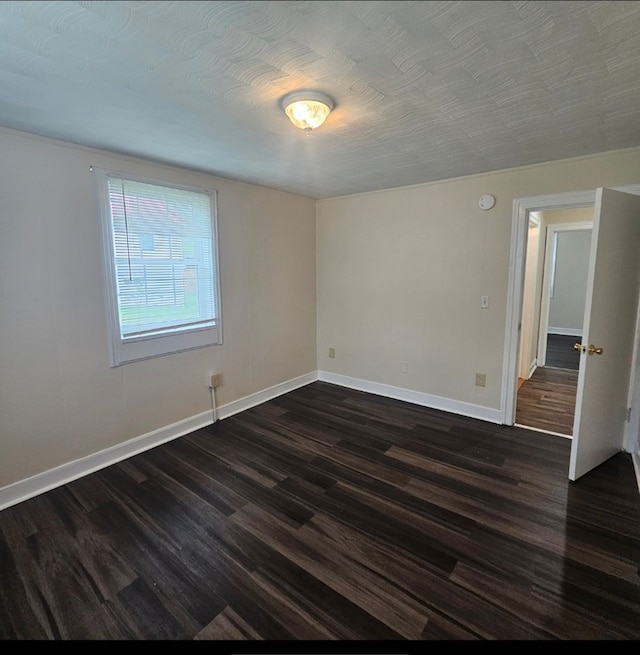 empty room with baseboards and dark wood-type flooring
