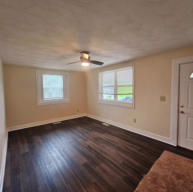 spare room with visible vents, baseboards, ceiling fan, and dark wood finished floors