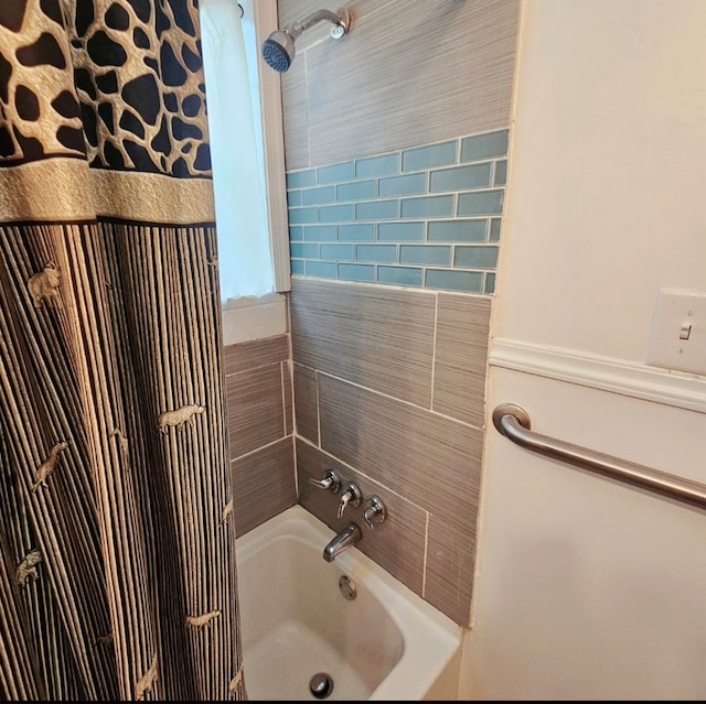 bathroom with shower / bathing tub combination and a wainscoted wall