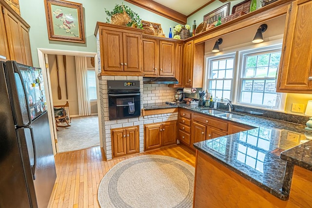 503 Court St, Abingdon, VA 24210 - kitchen with black appliances, brown cabinets, under cabinet range hood, light wood-type flooring, and backsplash
