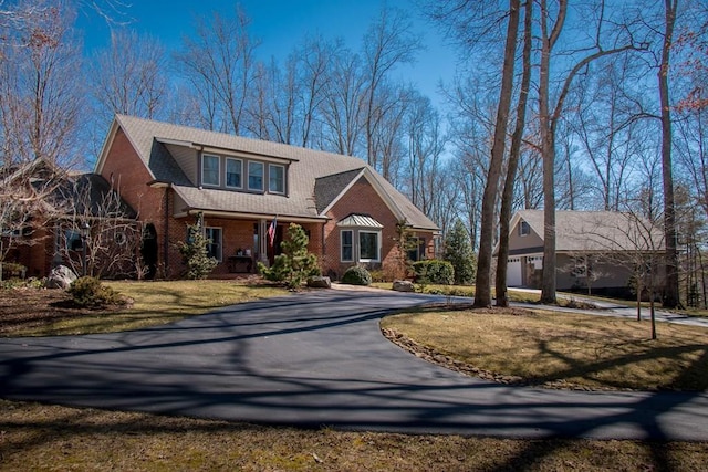 view of front of home with aphalt driveway, covered porch, brick siding, a front yard, and a garage