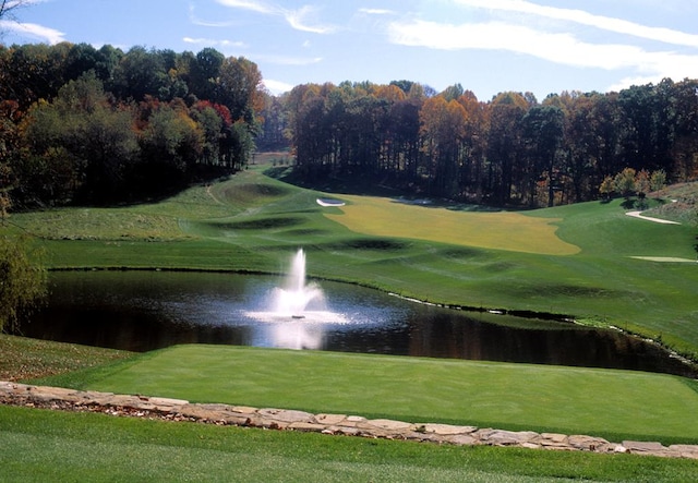 view of property's community featuring golf course view, a lawn, and a water view