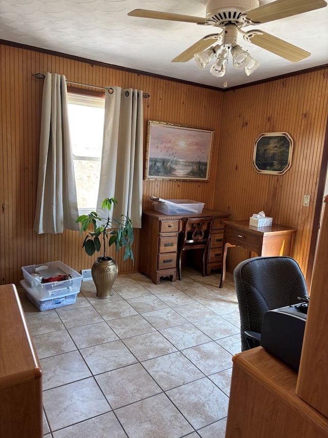 office space with crown molding, a ceiling fan, wooden walls, and light tile patterned flooring